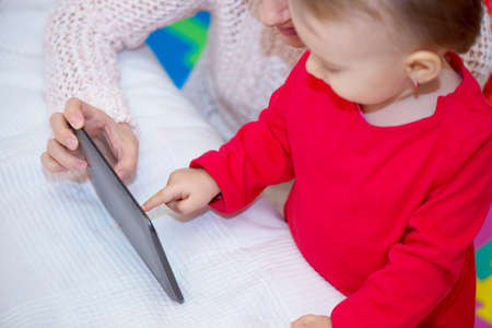 Woman showing the baby how to use a tabletの写真素材