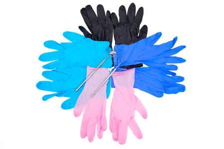 Colorful gloves with dental instruments isolated on white background