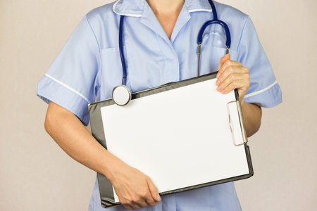 Female doctor in blue uniform holding a clipboard, isolated