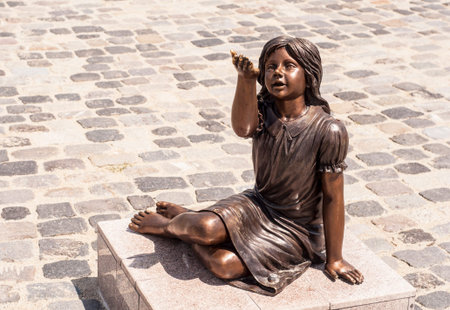 Statue of a little girl holding the hand up, in a parkの写真素材