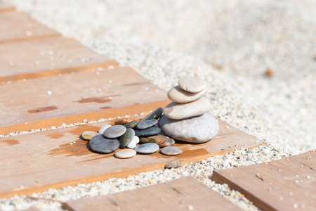 Arrangement with stones on wooden slats on the sand of a beachの写真素材
