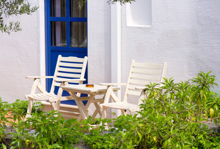 Two chairs and a table near a white wall outdoors in Greece