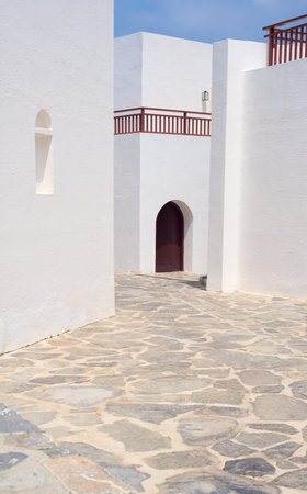 Beautiful Greek architecture, white walls, blue sky, narrow street and perfect geometry of shapes