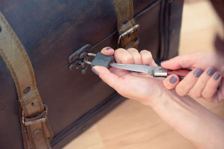 Close up of woman's hands opening an old chest with a knifeの写真素材