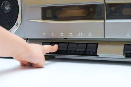 Child pushing the play button of an old cassette playerの写真素材