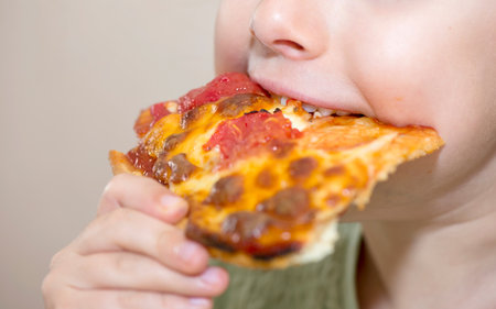 Close up of the mouth of a child eating a slice of pizzaの写真素材