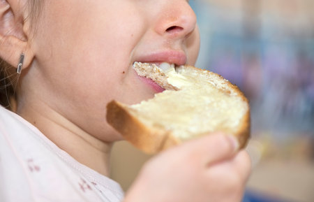 Close up of a mouth of a caucasian little child eating bread and honeyの写真素材