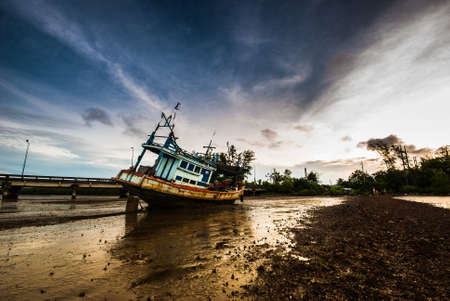 Fishing boat ran aground on the mud beach with the morning lightの写真素材