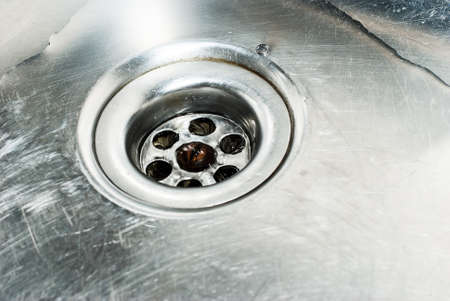 Stainless steel sink plug hole close up with waterの写真素材