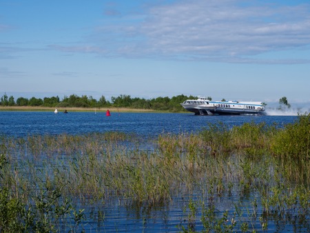 A speedboat moves through the lake against the background of the sky and the green forest.の写真素材