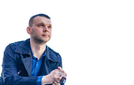 A young man in a blue coat and shirt stands on the landing and looks into the distance. A young, handsome businessman in a business center. Isolated photo.の写真素材