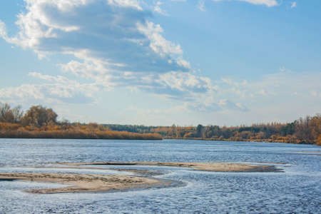 Beautiful clouds in the blue sky. Autumn landscape on a bright sunny day. Sandy islands on the river.の写真素材
