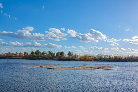Beautiful clouds in the blue sky. Autumn landscape on a bright sunny day. Yellow forest on the...