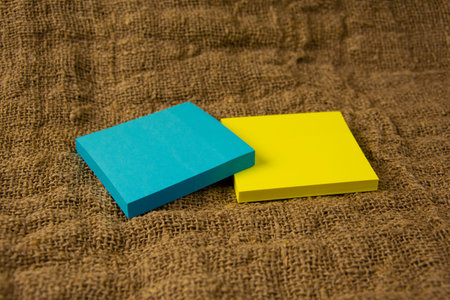 Blue and yellow stickers lie on a gray coarse fabric. Yellow and blue stationery on yellowed old...