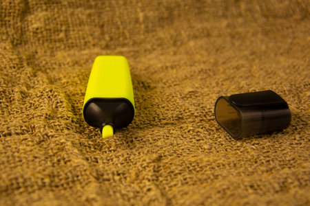 The yellow highlighter lies on a gray coarse fabric. Stationery on yellowed old burlap.