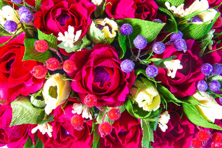 A beautiful bouquet of flowers made of red and yellow roses, green leaves and red and purple berries. top view. close-up.の写真素材