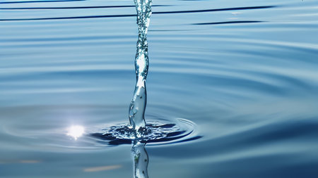 A stream of clear water flows into a beautiful blue lake. Beautiful waves radiate from the running jet of water. generated AI.の素材