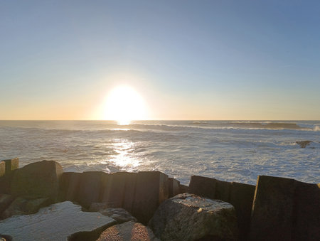 Rocky ocean shore. Evening ocean. The sun sets below the horizon. Beautiful sea waves.の写真素材