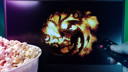 Kyiv. Ukraine. 11/10/2023: Person watching House of the Dragon on TV with popcorn and remote...