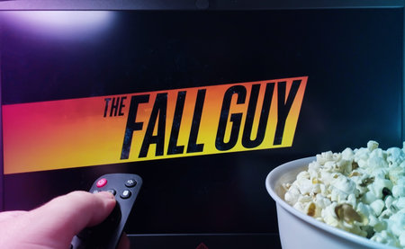 Kyiv. Ukraine. 11/10/2023: Person watching The Fall Guy on TV with popcorn and remote control. Stock...