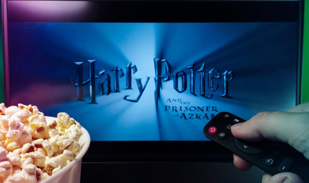 Kyiv. Ukraine. 11/10/2023: Person watching Harry Potter on TV with popcorn and remote control. Stock...