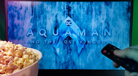 Kyiv. Ukraine. 11/10/2023: Person watching Aquaman and the Lost Kingdom movie on TV with popcorn and...