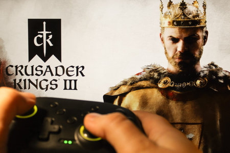 A gamer plays Crusader Kings III with a gamepad. Stock editorial photo with the game logo. Ukraine,...