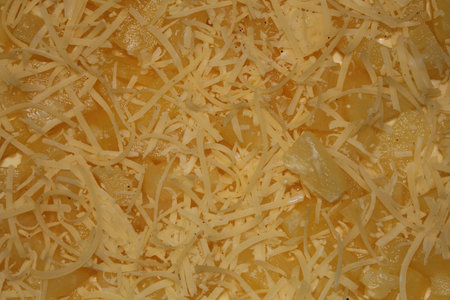 Golden cooked pasta is generously layered with finely shredded cheese, creating a melty and inviting...