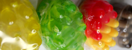 Colorful gummy candies resembling fruits sit in a row, highlighting their bright hues and unique shapes, inviting a sense of fun and sweetness.の写真素材