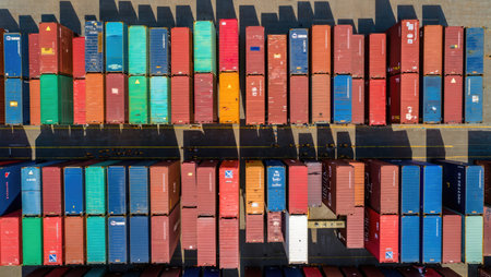 Stacked shipping containers in various vibrant colors form a symmetrical industrial pattern. The sunlight casts long shadows, creating a dynamic urban composition. Generative AI.の素材