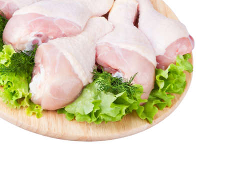 Raw chicken legs with green salad on a wooden boardの写真素材