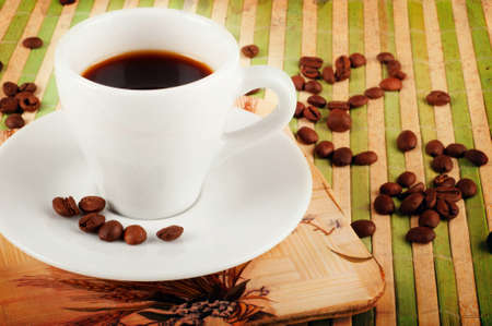 Vintage background with coffee cup and coffee beans  on green bamboo standの写真素材