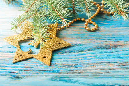 Golden Christmas decorations and fir branch on a blue wooden backgroundの写真素材