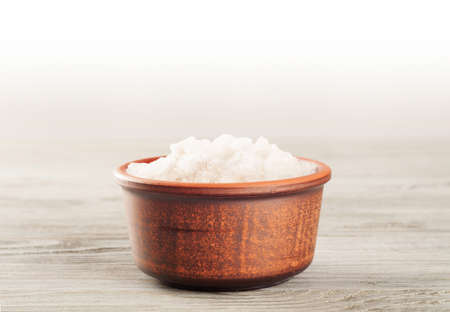 Aromatic bath salt in a clay cup on a wooden surfaceの写真素材