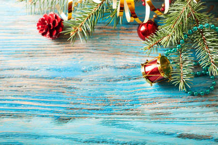 Red Christmas decorations and fir branch on a blue wooden backgroundの写真素材