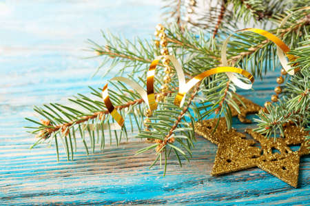 Golden Christmas decorations and fir branch on a blue wooden backgroundの写真素材