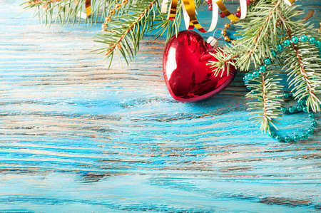 Red Christmas decorations and fir branch on a blue wooden backgroundの写真素材