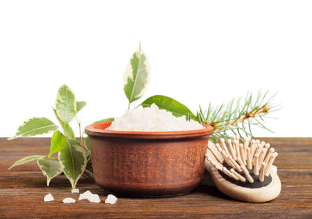 Aromatic bath salt in a clay cup and comb on a wooden backgroundの写真素材