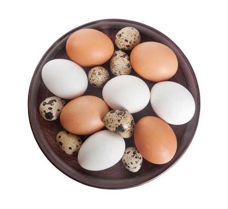Quail and chicken eggs in a clay plate isolated on a white backgroundの写真素材