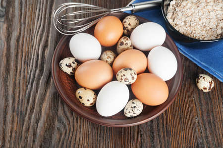 Quail and chicken eggs in a clay plate on a wooden backgroundの写真素材