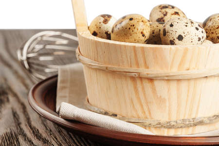 Quail eggs in a wooden bucket on a wooden tableの写真素材