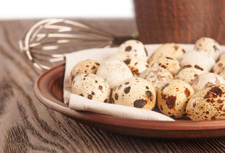 Quail eggs in a clay plate on a wooden tableの写真素材