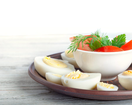 Boiled hen eggs in a clay dish on a wooden background