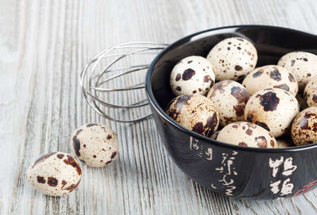Quail eggs in a black dish on a wooden background.の写真素材