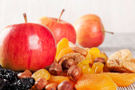 Ripe red apples on a wooden background. Juicy apples, nuts and dried fruits on a table.の写真素材