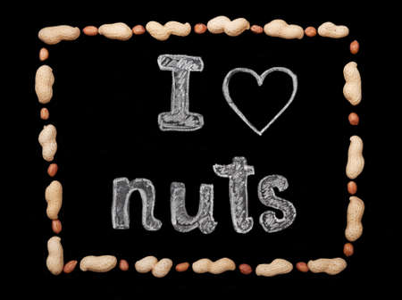 Frame of peanuts on a black background and chalk inscription "I love nuts"の写真素材