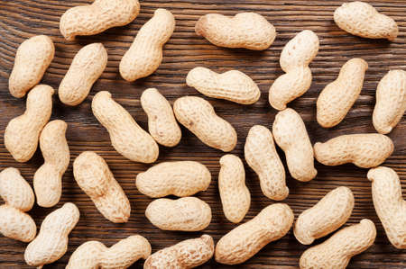 Peanuts in shell scattered on a wooden table. Background with nuts.の写真素材