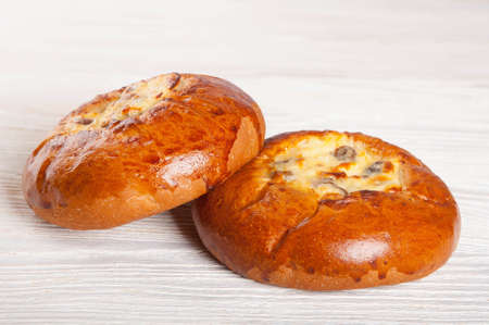 Two fresh homemade buns with cottage cheese and raisins on a wooden backgroundの写真素材