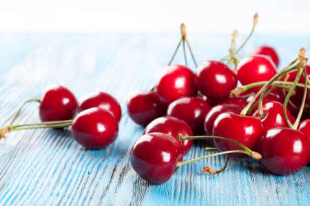 Red ripe sweet cherry on a blue wooden backgroundの写真素材