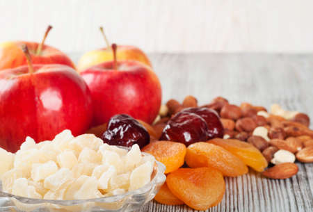 Pieces of dried pineapple, apricot, nuts and red apples on a wooden backgroundの写真素材